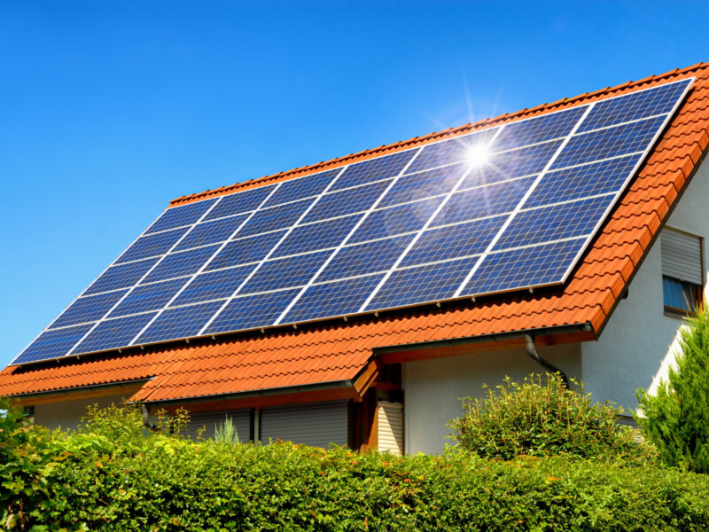 Solaranlage auf einem Hausdach unter dem strahlend blauen Himmel, mit der Reflektion der Sonne